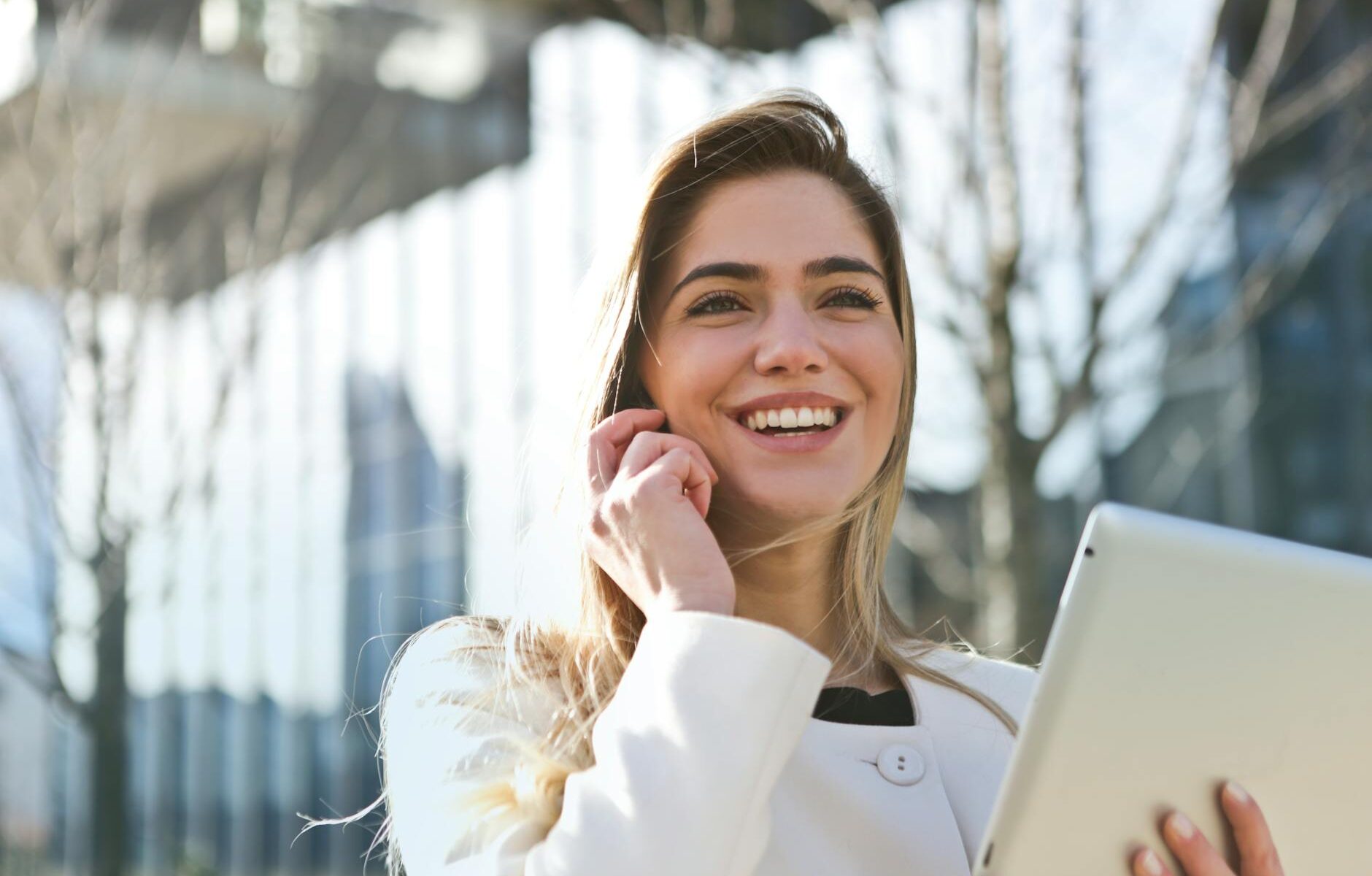 woman in white blazer holding tablet computer